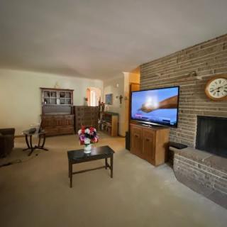 A cozy living room with a brick fireplace, television, and classic furniture.