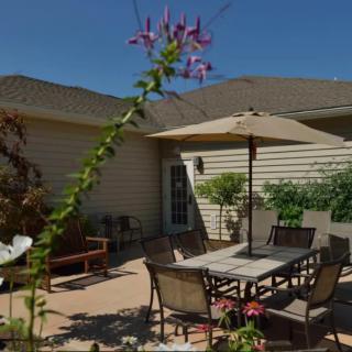 A cozy patio area with outdoor furniture and garden plants under a clear blue sky.