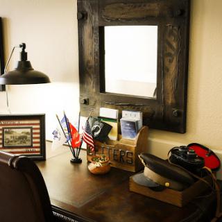 A well-organized desk featuring a mirror, flags, and personal memorabilia.