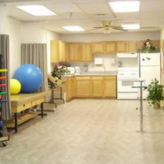A rehabilitation space with kitchen facilities and exercise equipment, including large therapy balls.