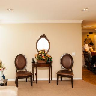 A cozy living room setup with two chairs, a small table, and an oval mirror on the wall.
