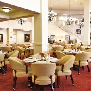 An elegant restaurant dining room with neatly arranged tables and chairs, highlighted by decorative chandeliers.