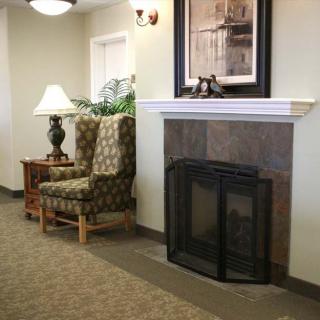 A cozy living room features a fireplace with an elegant chair and lamp nearby.