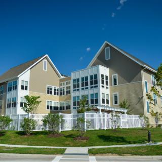 A modern suburban residential building with a fenced yard and landscaped surroundings.