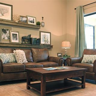 Cozy living room with a leather sofa, armchair, and wooden coffee table, adorned with personal photographs and decor on the shelf.