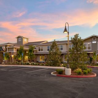 A scenic view of a building at sunset with a parking lot in the foreground.