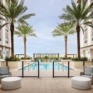 A luxurious outdoor swimming pool surrounded by palm trees and modern architecture, offering a relaxing lounge area.