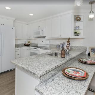 A modern kitchen featuring white cabinets and granite countertops.