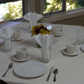 A dining table set with plates, cups, cutlery, and decorated with flowers.