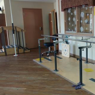 A dedicated physical therapy space featuring parallel bars for rehabilitation exercises.