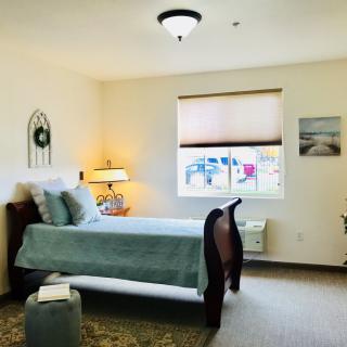 A cozy bedroom with a neatly made bed, decorative elements, and a window view.
