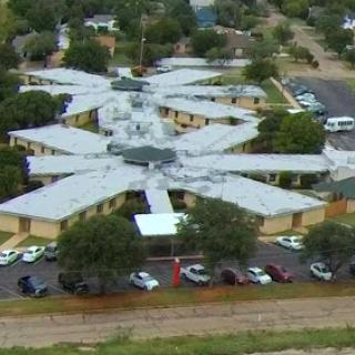 An aerial view of a uniquely designed community building surrounded by greenery.