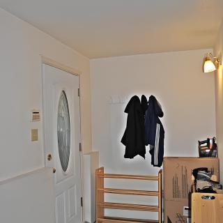 A small hallway with an entrance door, coat rack, and shoe storage.