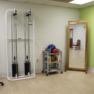 A rehabilitation room featuring exercise equipment and a mirror.