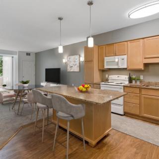 A modern kitchen with an open dining area, featuring a central island and pendant lights.
