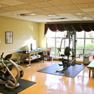 A well-lit gym with exercise equipment, including a stationary bike and weight machine.