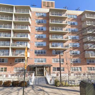 A multi-story residential apartment building with numerous balconies and a brick exterior.