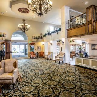 A spacious hotel lobby with elegant chandeliers, intricate carpeting, and comfortable seating areas.
