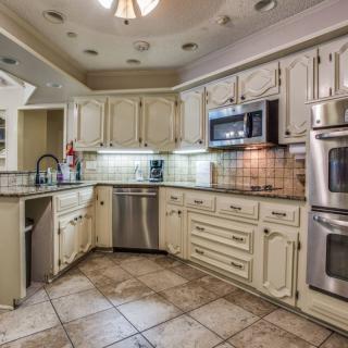 A spacious kitchen featuring white cabinets, tile flooring, and stainless steel appliances.