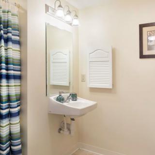 A clean bathroom with a wall-mounted sink, mirror, and colorful shower curtain.
