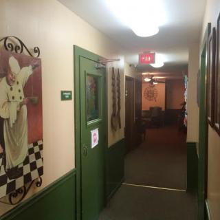 A decorated hallway with paintings and a green door under warm lighting.
