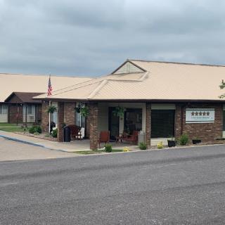 A brick building with a tan roof and outdoor seating, set against a cloudy sky.