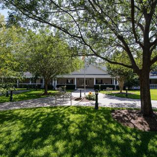 A picturesque house with a lush green yard and mature trees.