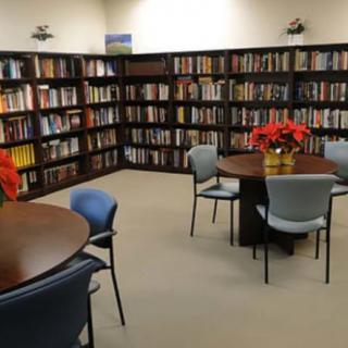 A cozy library with shelves full of books, tables, and chairs for reading.