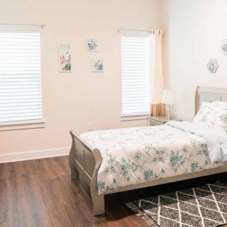 A cozy bedroom with a floral-patterned bedspread, wooden flooring, and minimalistic decor.