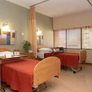 A hospital room with two beds and a curtain divider.