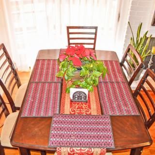 A dining table elegantly set with patterned placemats and a plant centerpiece.
