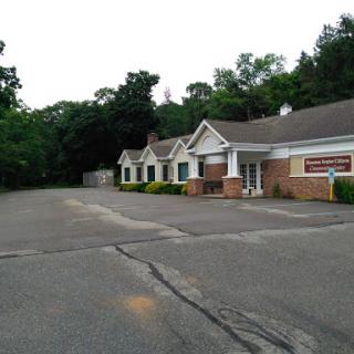 A quiet commercial building surrounded by greenery, set on a spacious lot.
