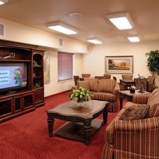 A cozy living room with a television, sofas, and a coffee table on a red carpet.