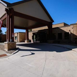 A building entrance with a large canopy and driveway on a clear day.