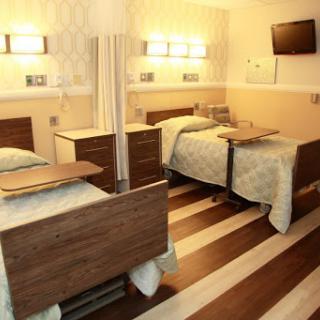 A well-equipped hospital patient room featuring two beds, designed for comfort and functionality.