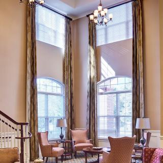 A spacious living room with high ceilings, large windows, and elegant decor.