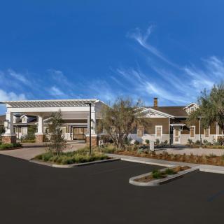 A modern building surrounded by landscaped greenery under a clear blue sky.