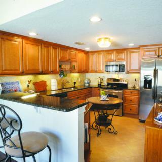 A modern kitchen with wooden cabinets, granite countertops, and stainless steel appliances.