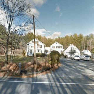 A residential area with white houses surrounded by trees and a clear sky.