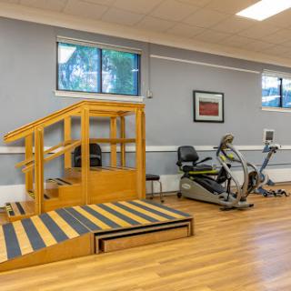 A well-equipped fitness area featuring a wooden ramp for rehabilitation and an elliptical machine.