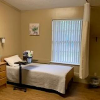 A simple hospital room with a bed, bedside table, and window.