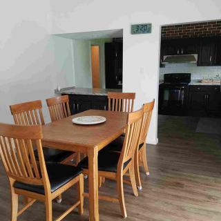A modern dining area featuring a wooden table and chairs, leading into a sleek kitchen.