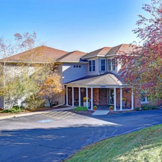 A two-story house with a covered entrance surrounded by autumn foliage.