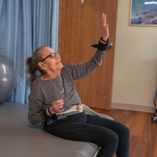 An elderly woman participates in a physical therapy session, demonstrating her commitment to rehabilitation and wellness.