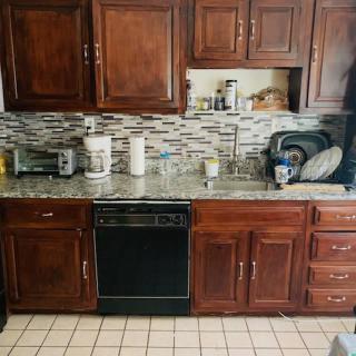 A kitchen featuring wooden cabinets, a tiled backsplash, and various appliances on the countertop.