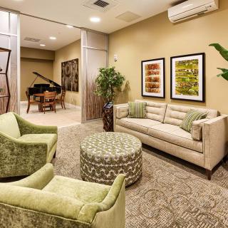A cozy living room with elegant furniture and a grand piano in the background.