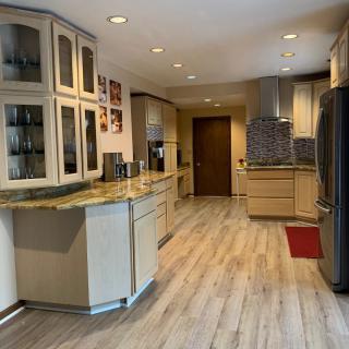 A modern kitchen with wood flooring, sleek cabinets, and contemporary appliances.