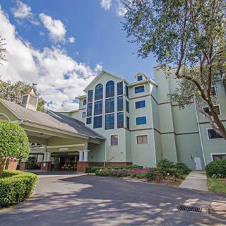 A hotel building with a covered entrance surrounded by trees and a clear sky.