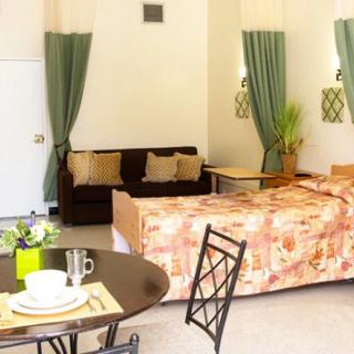 A cozy hotel room with a bed, sofa, and dining area.