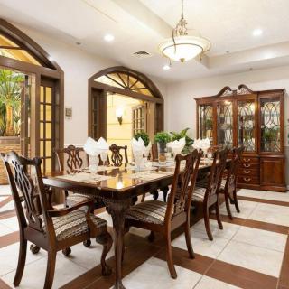 Elegant dining room with a large wooden table and chairs, illuminated by a chandelier.